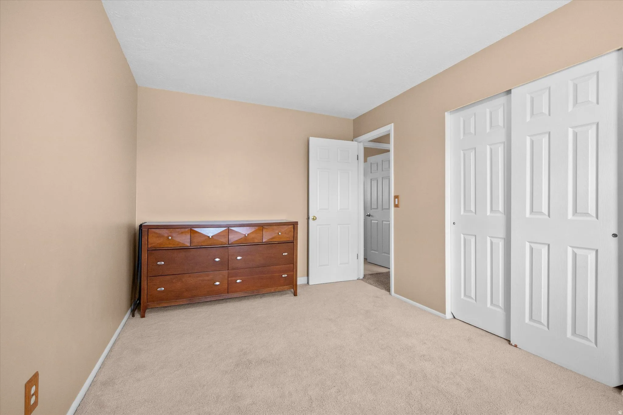 Bedroom featuring light carpet and a closet