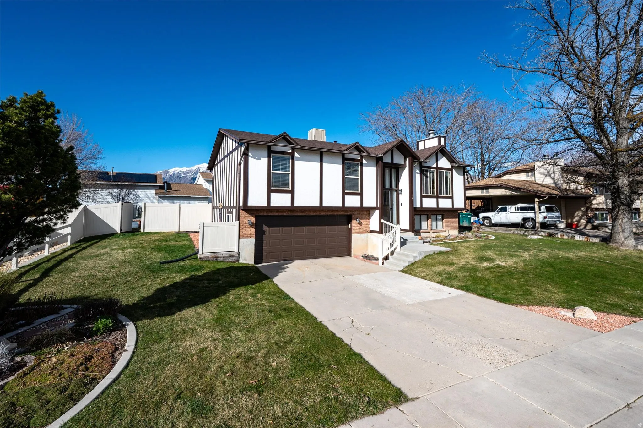 View of front of property featuring a chimney, a garage, concrete driveway, stucco siding, and brick siding