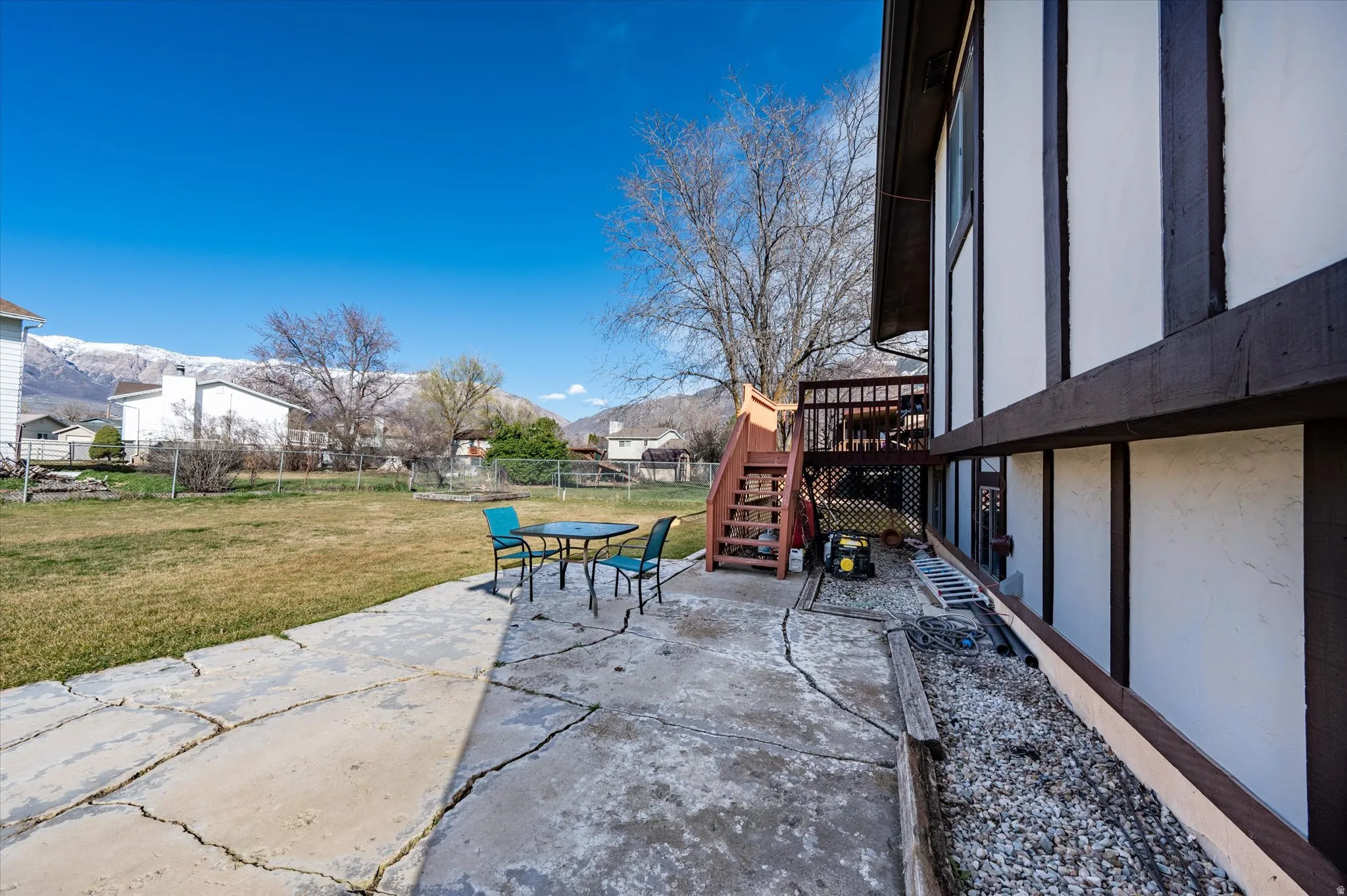 Fenced backyard featuring a patio, a deck with mountain view, outdoor dining space, and a residential view
