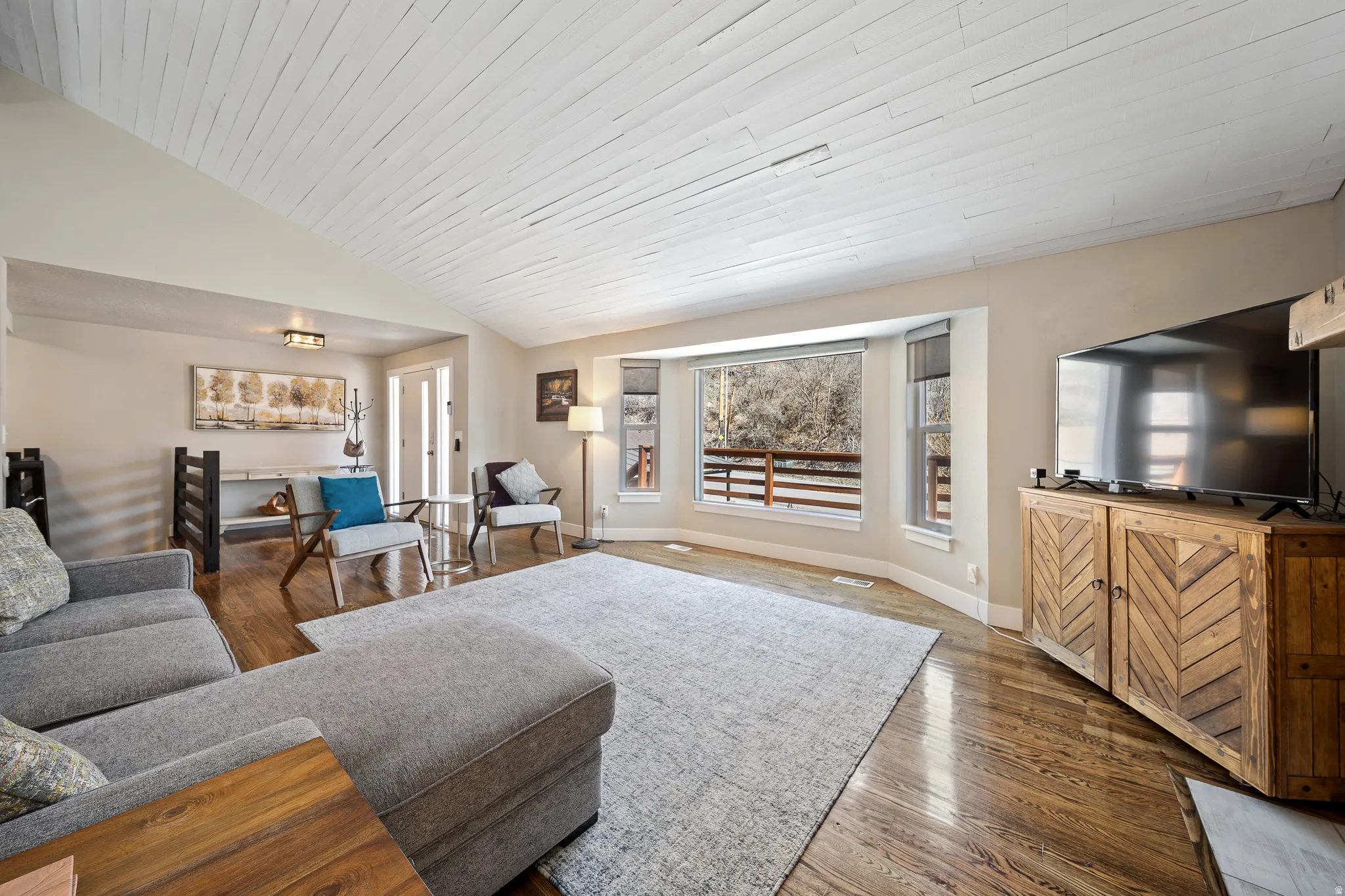 Living room with dark wood-style floors and a vaulted wooden ceiling