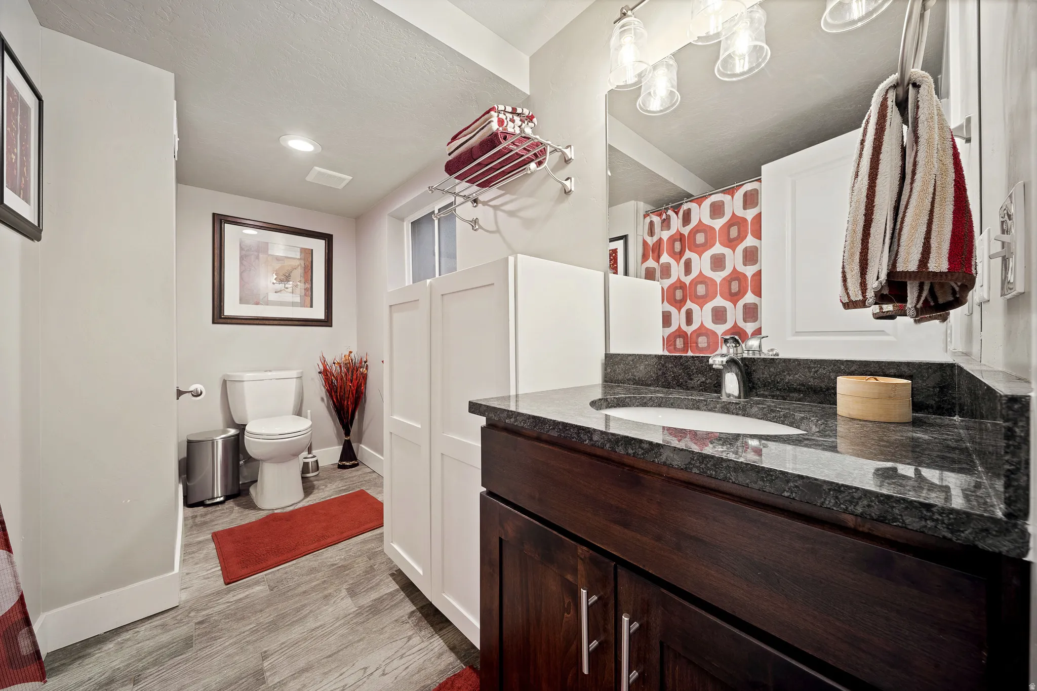 Bathroom with curtained shower, vanity, and light wood-style flooring