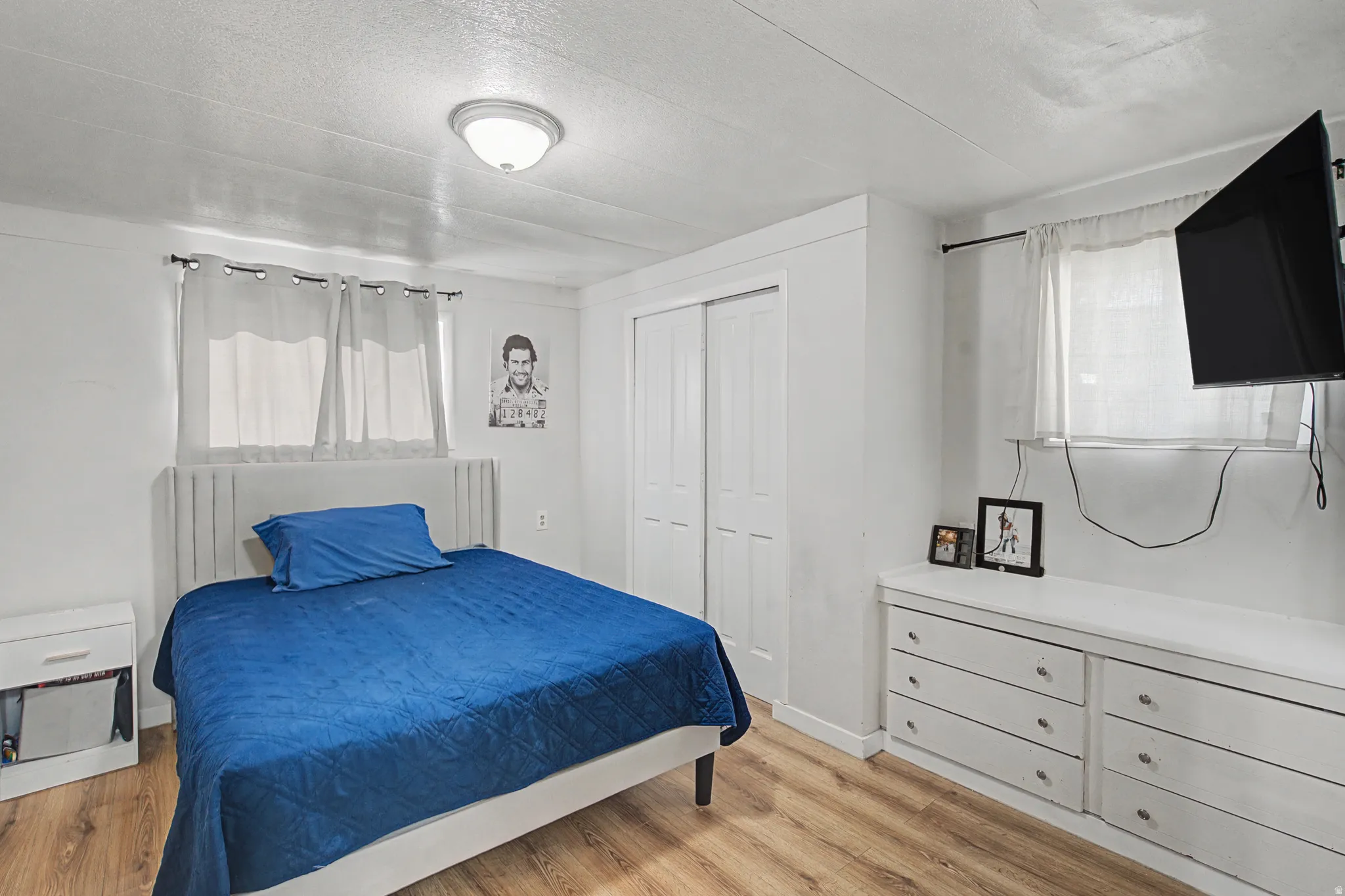Bedroom with a textured ceiling, light wood-type flooring, and a closet