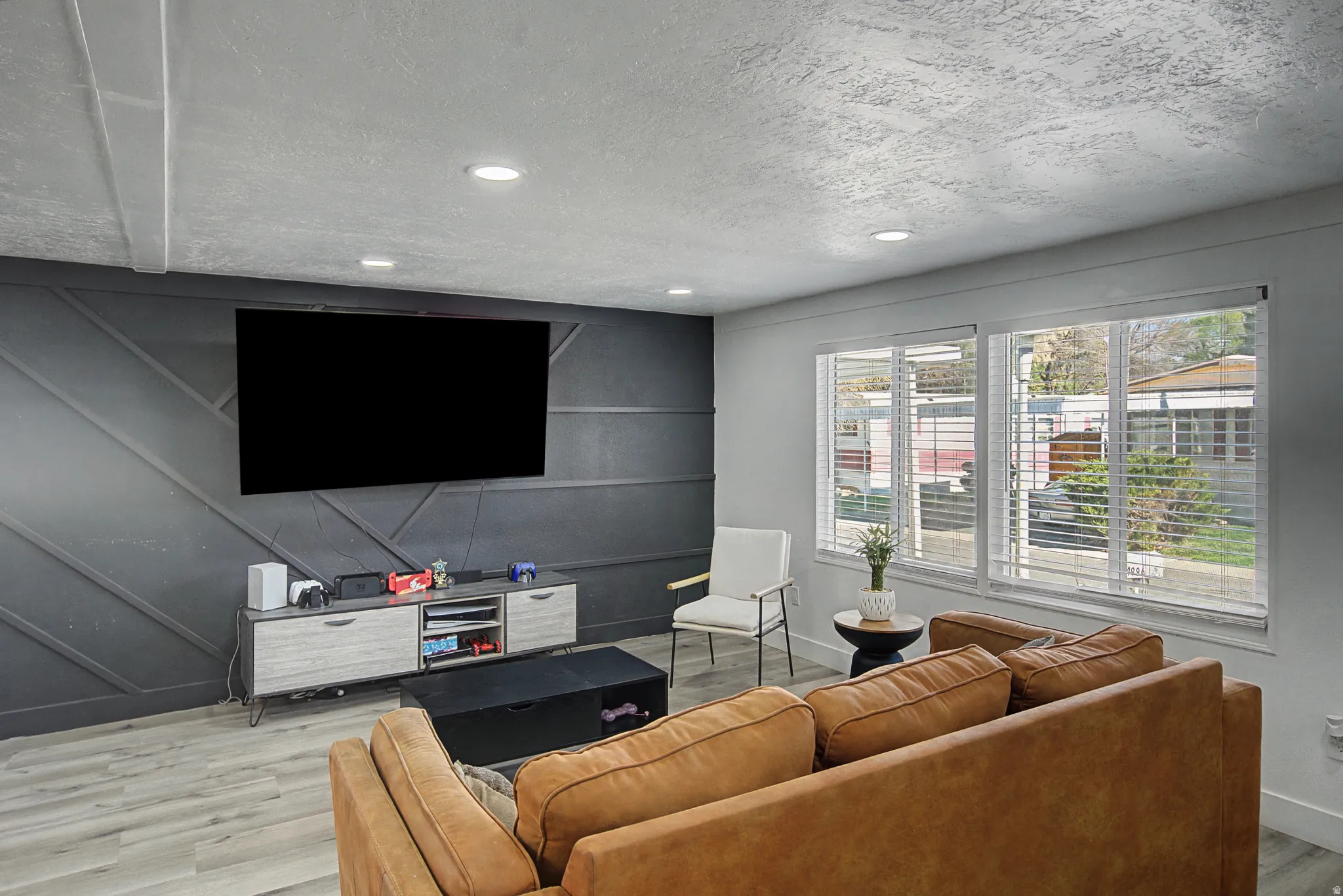 Living area featuring an accent wall, wood finished floors, recessed lighting, a textured ceiling, and a decorative wall