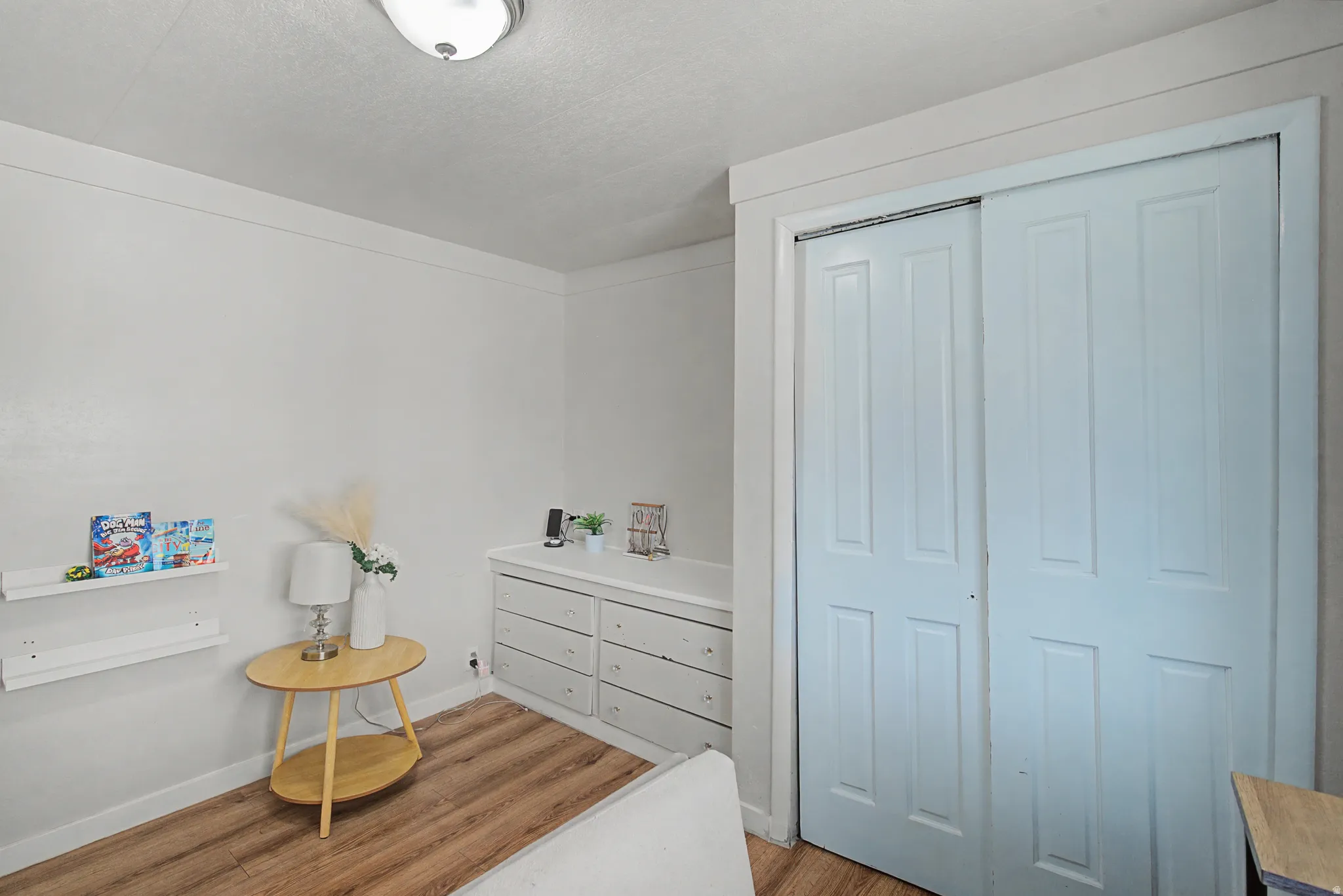 Bedroom featuring light wood-style flooring, a closet, and a textured ceiling