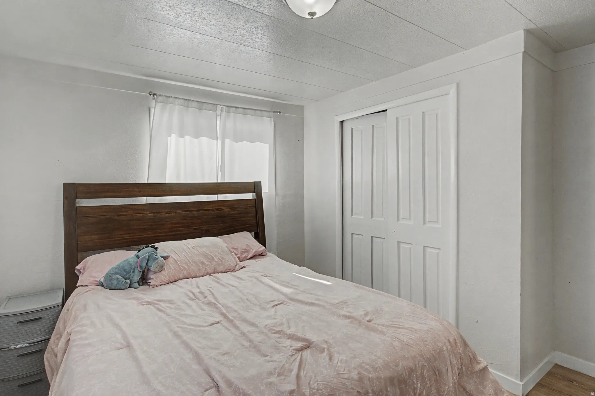 Bedroom featuring a closet, a textured ceiling, and wood finished floors