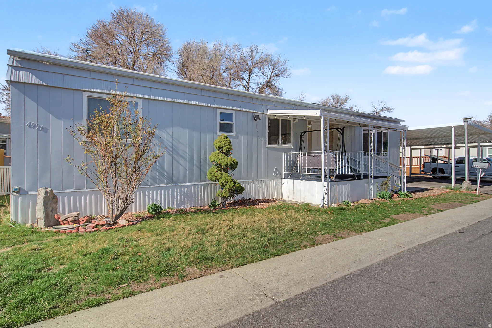 Manufactured / mobile home featuring a carport, a front lawn, and covered porch