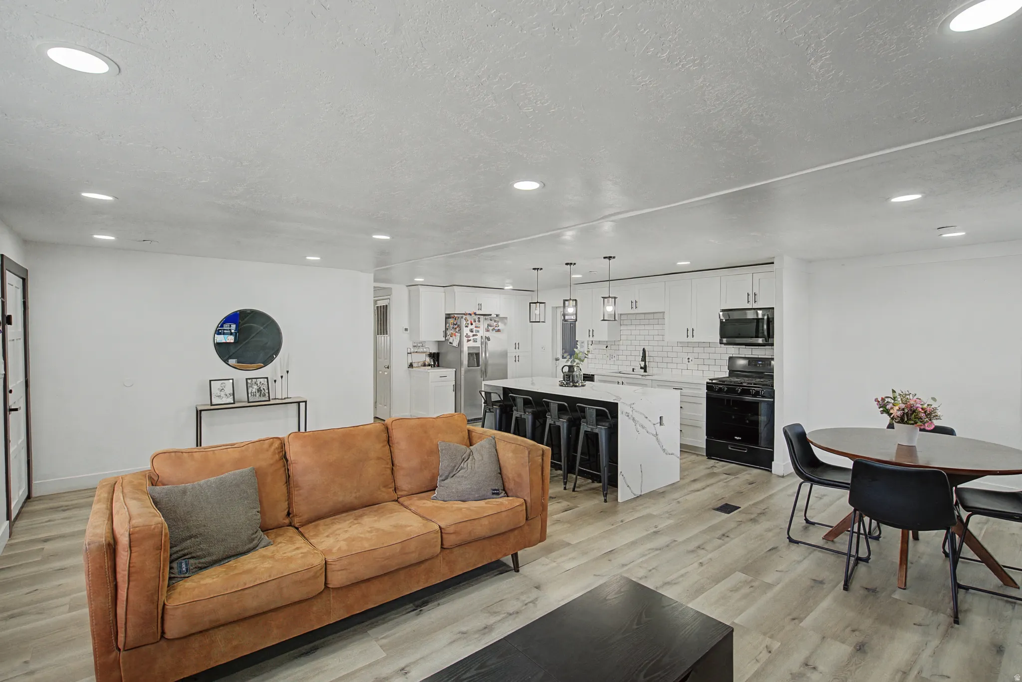 Living area featuring light wood-style flooring, recessed lighting, and a textured ceiling