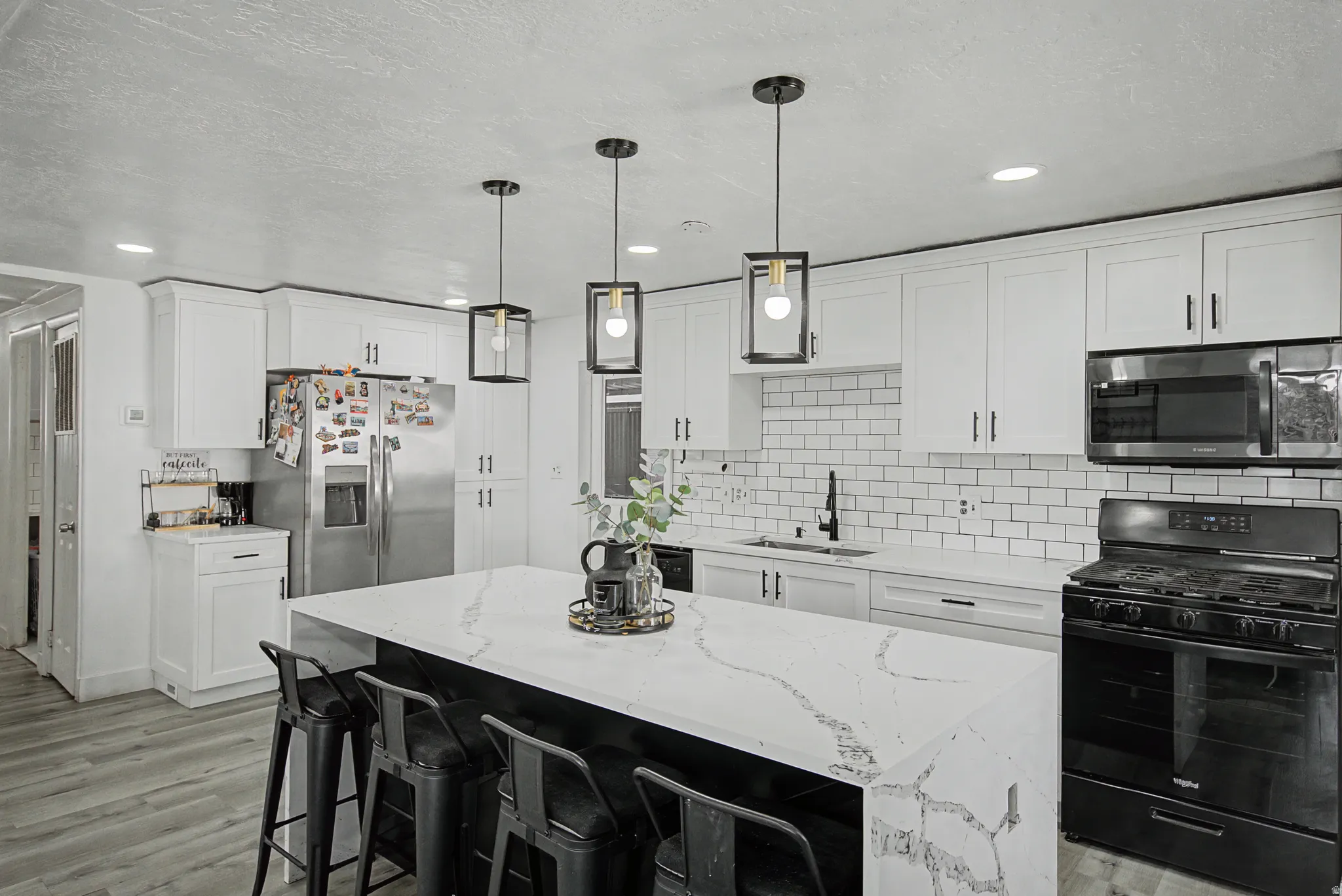 Kitchen featuring stainless steel appliances, light stone countertops, a breakfast bar area, a center island, and white cabinetry