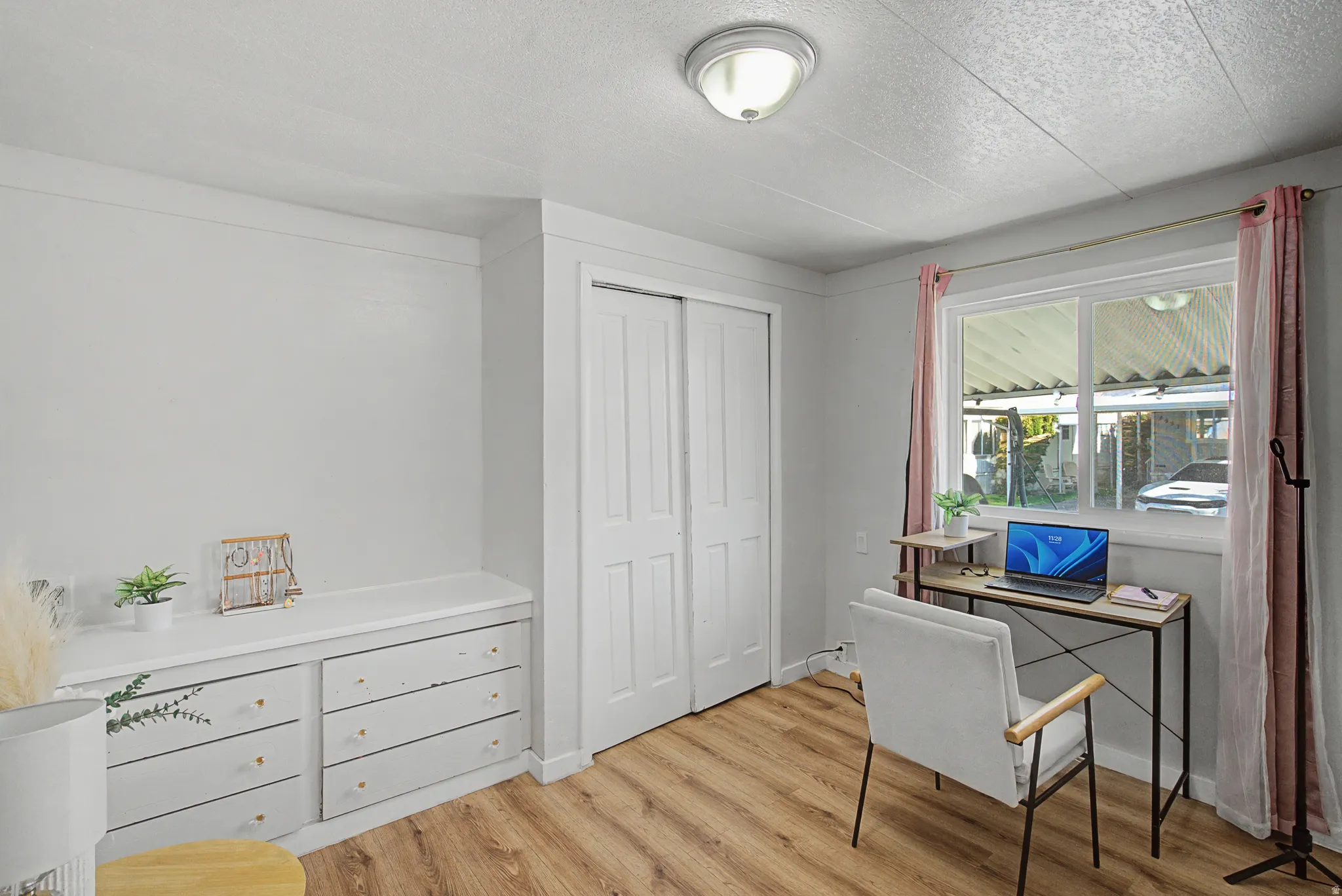 Home office with light wood finished floors and a textured ceiling