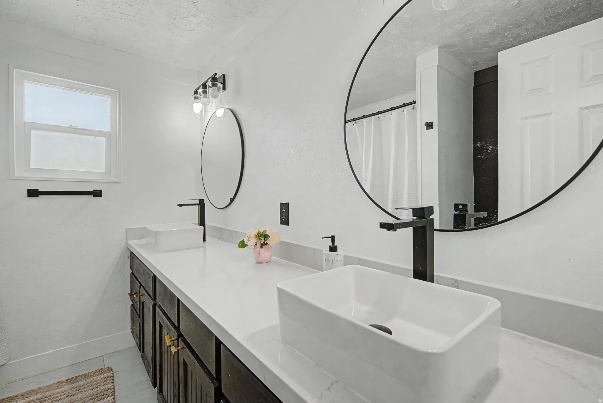 Bathroom with double vanity, a shower with shower curtain, and a textured ceiling