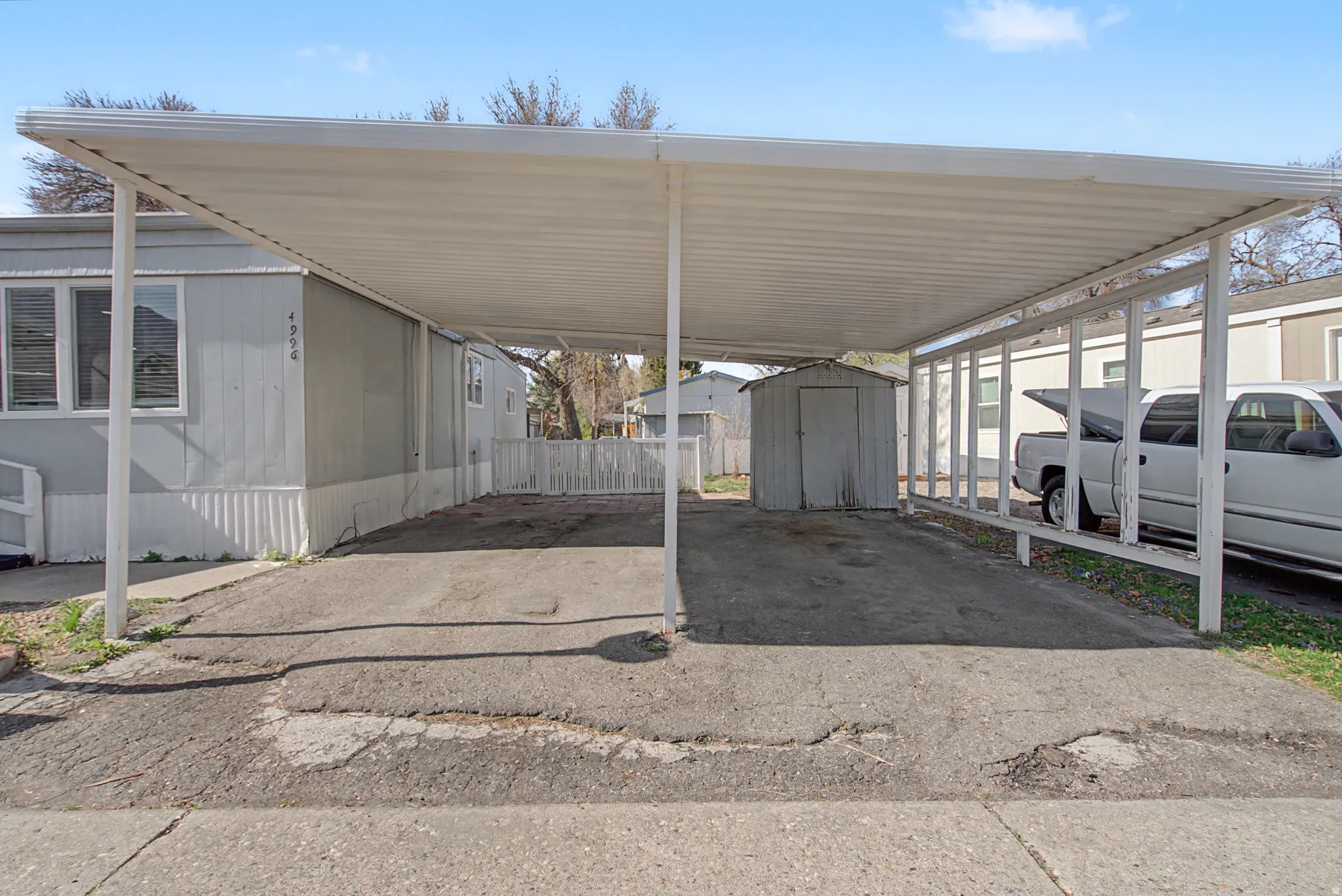 View of parking with a storage shed and a carport