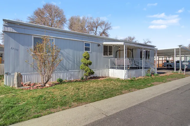 Manufactured / mobile home featuring a carport, a front lawn, and covered porch