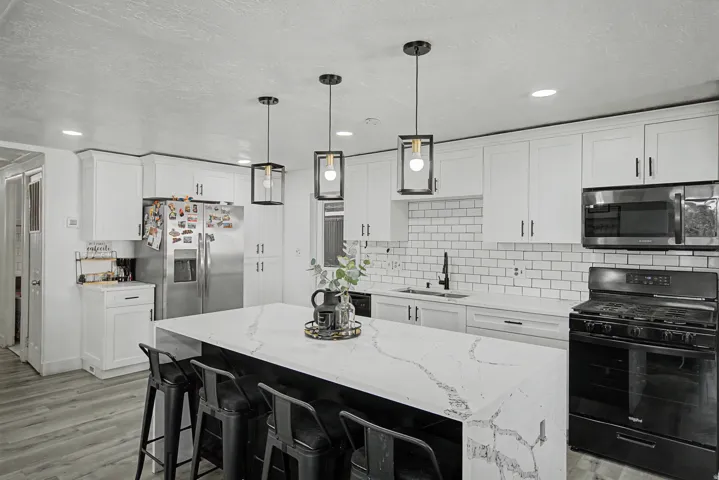 Kitchen featuring stainless steel appliances, light stone countertops, a breakfast bar area, a center island, and white cabinetry