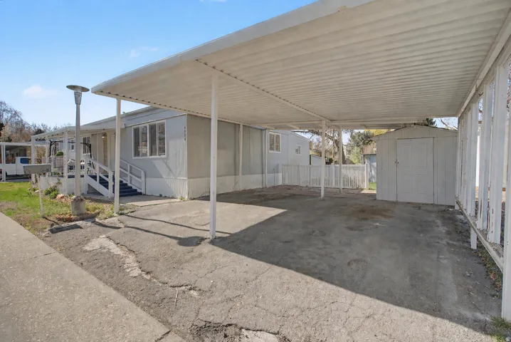 View of parking with a storage shed and a carport
