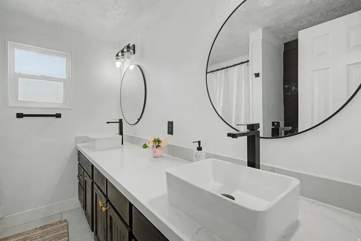 Bathroom with double vanity, a shower with shower curtain, and a textured ceiling