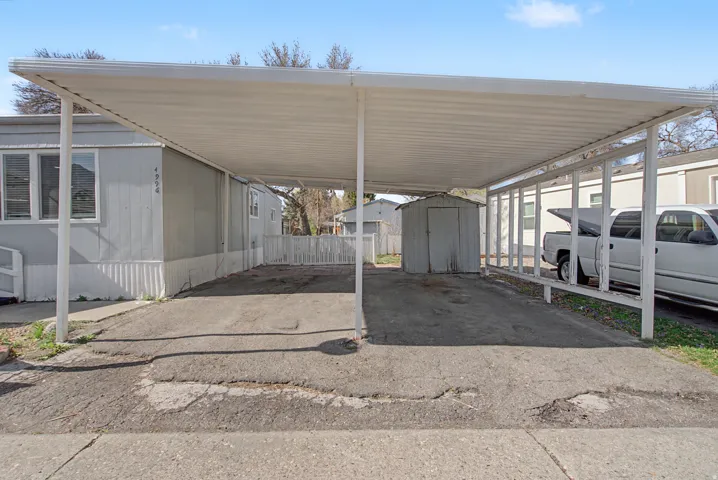 View of parking with a storage shed and a carport