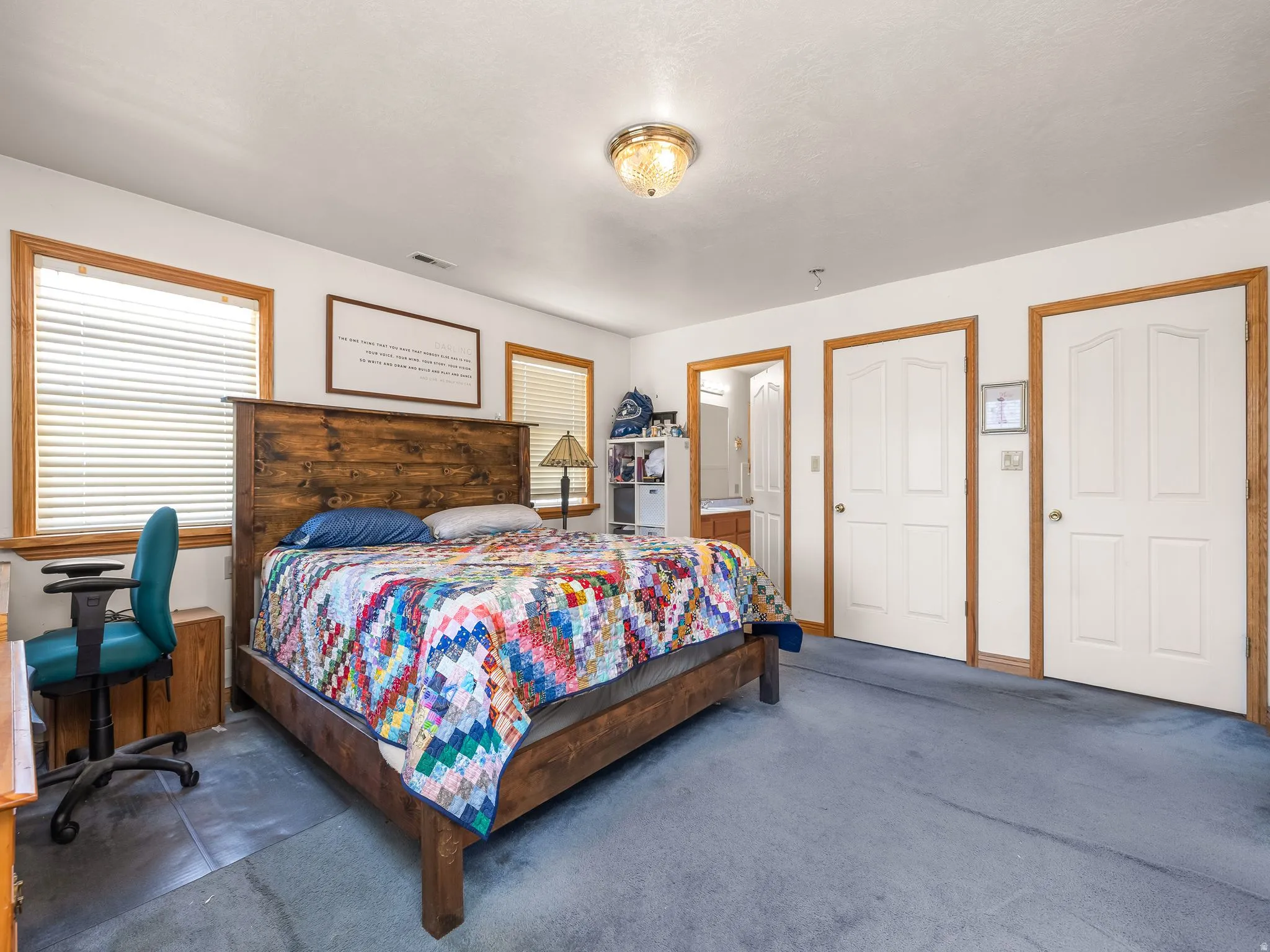 Carpeted primary bedroom with multiple windows and ensuite bathroom