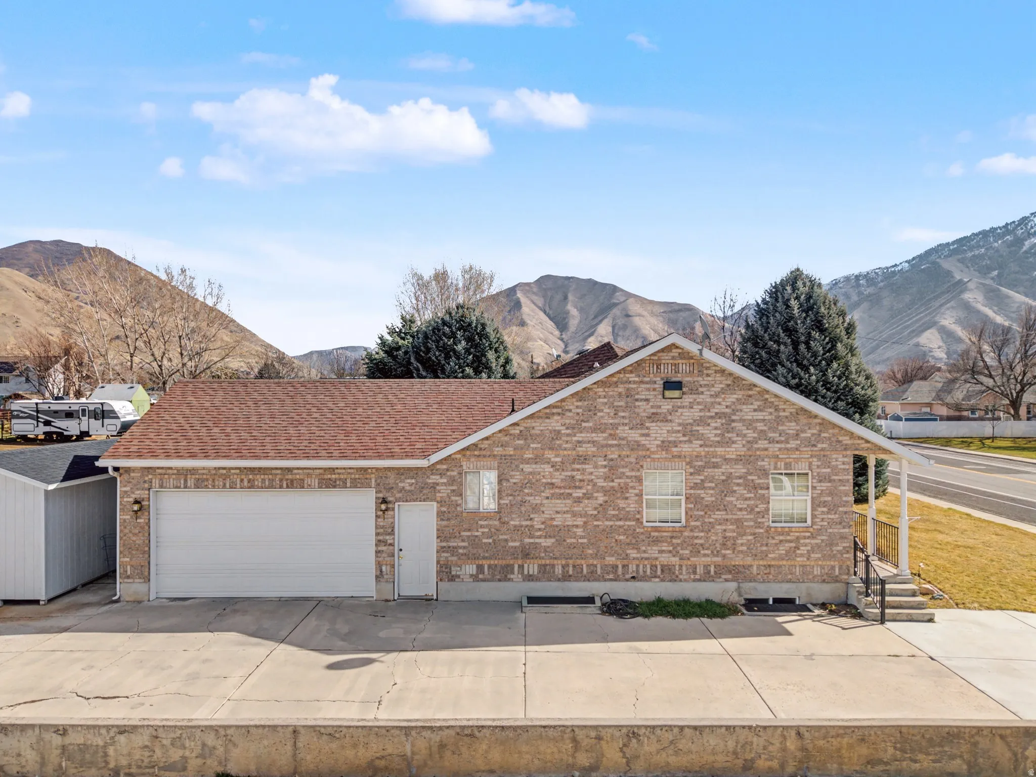 Ranch-style home featuring a mountain view, a garage, brick siding, concrete driveway, and roof with shingles