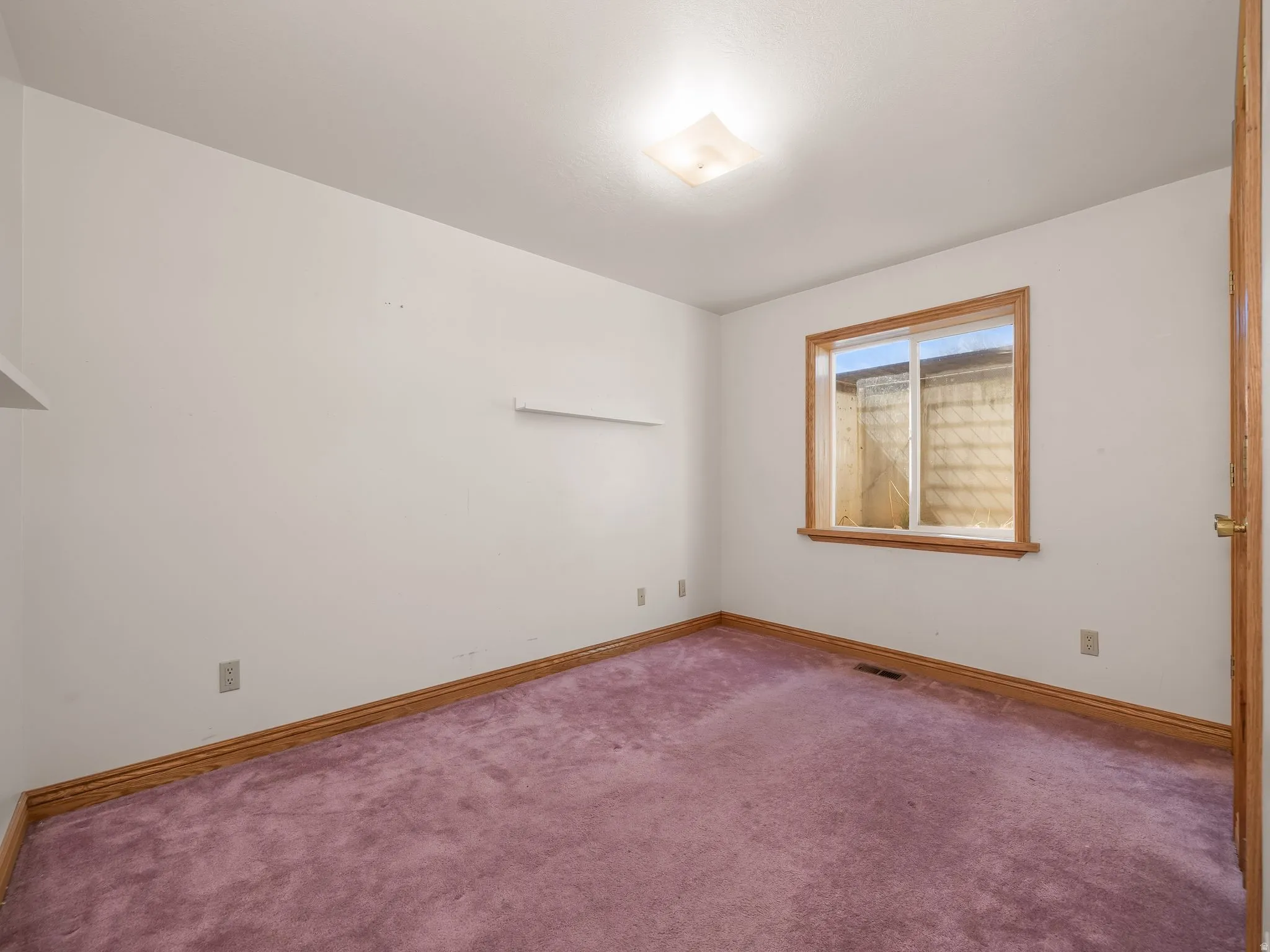 Carpeted spare room featuring baseboards