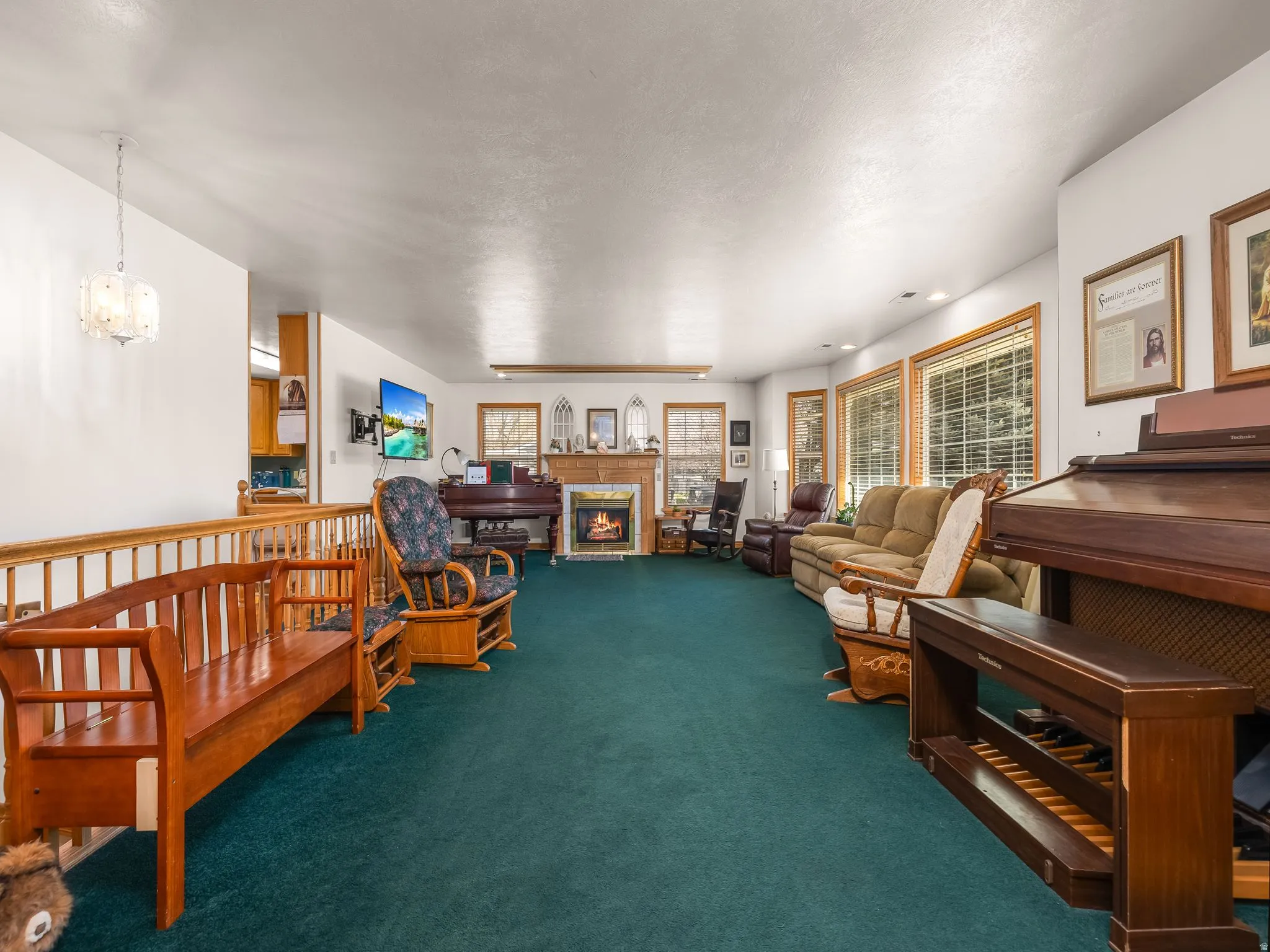 Carpeted living area featuring a warm lit fireplace