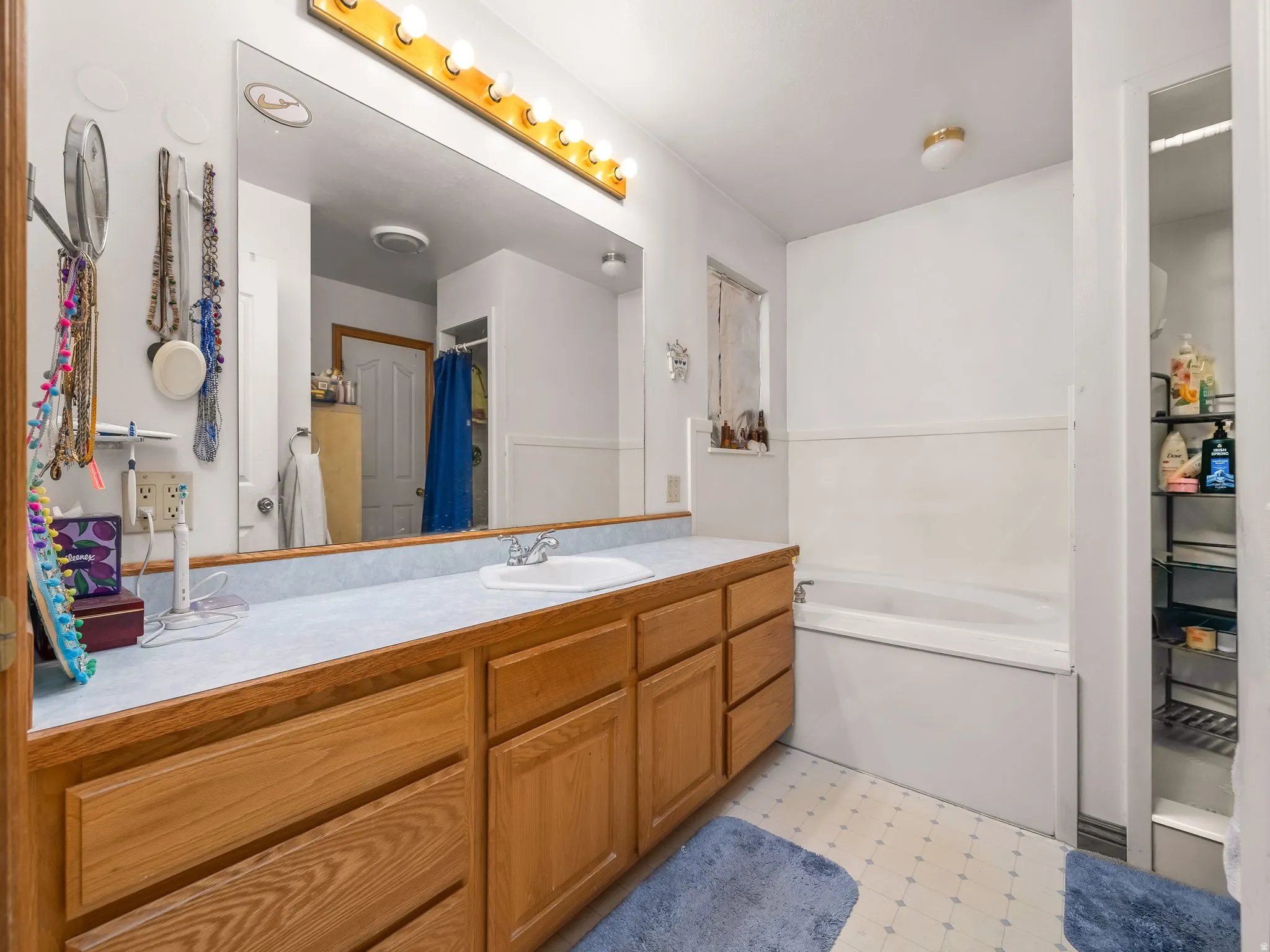 Full bath with vanity, light flooring, and a bath