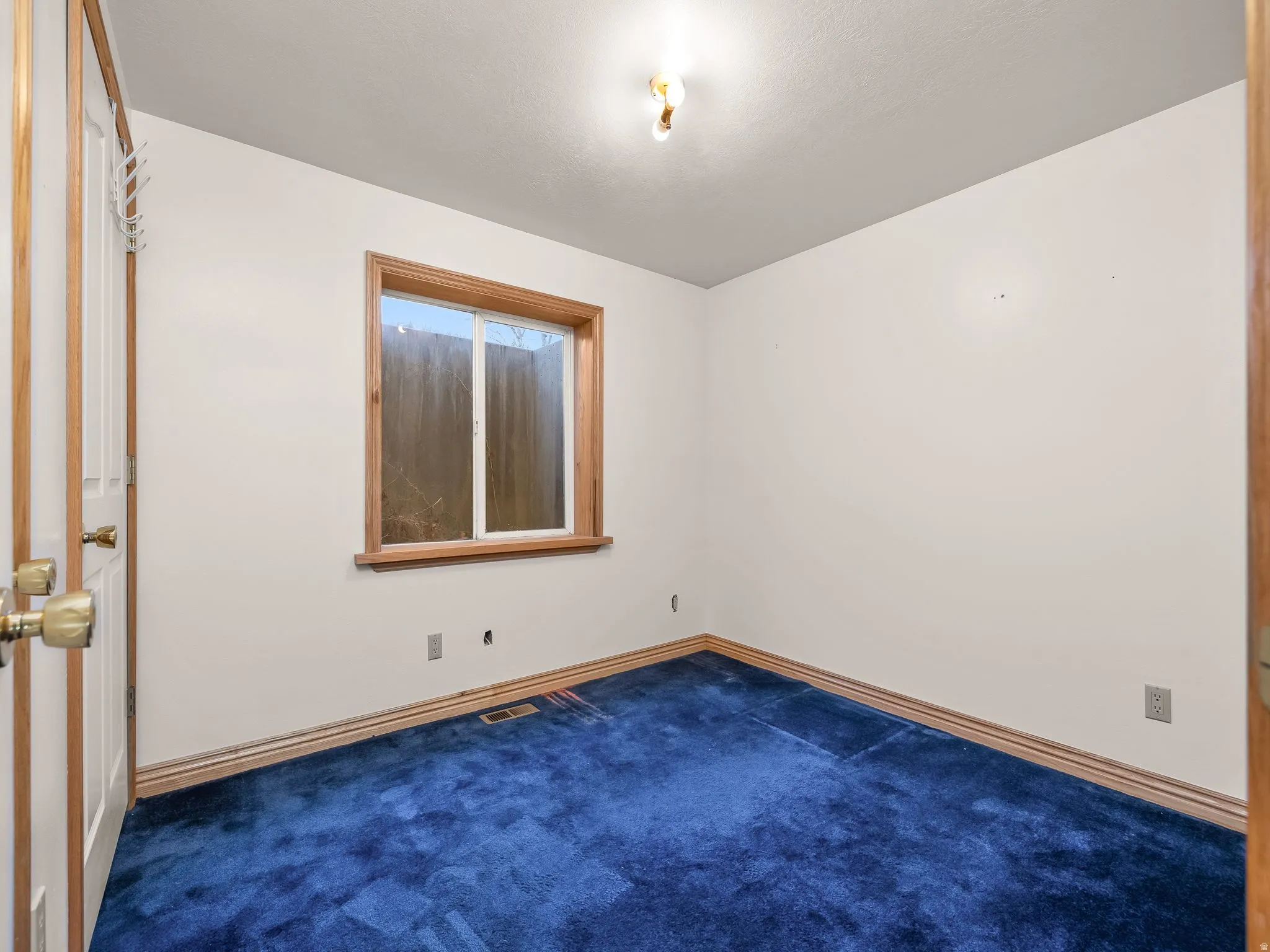 Unfurnished room with dark colored carpet and baseboards