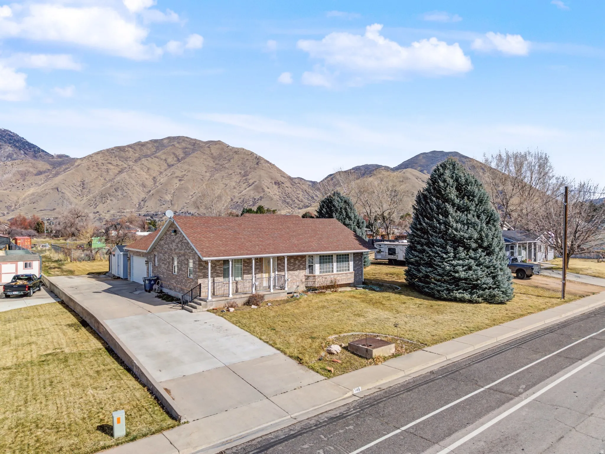 View of front of home featuring concrete driveway, a front yard, a porch, a mountain view, and a garage