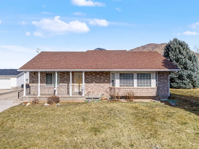 Ranch-style house with a porch, a front lawn, a shingled roof, and brick siding