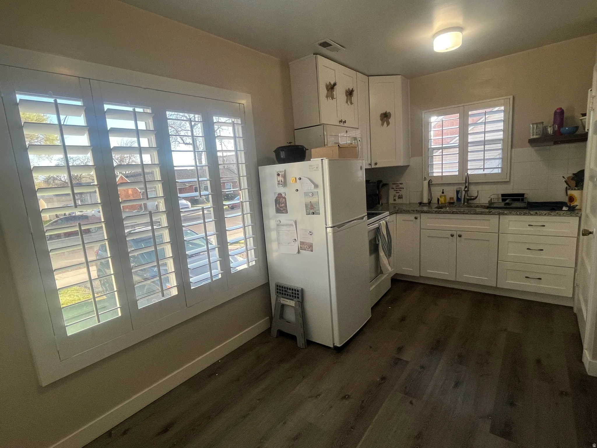 Kitchen featuring white cabinetry, white appliances, dark wood finished floors, and dark stone countertops