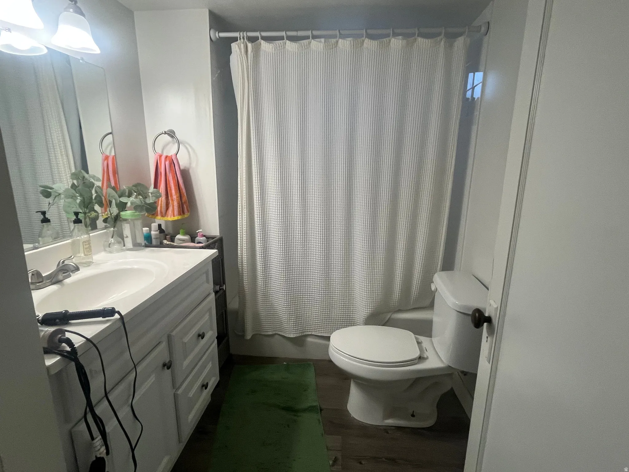Full bathroom with vanity, shower / tub combo with curtain, and dark wood-style flooring