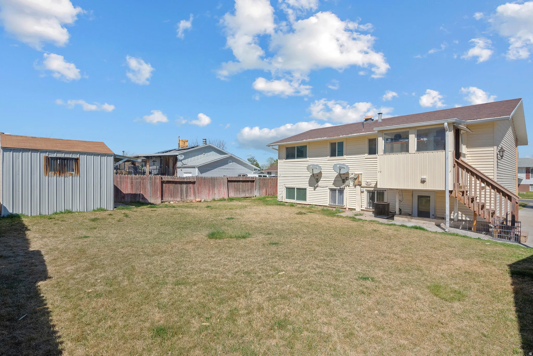 Back of property featuring a patio, a fenced backyard, a storage unit, and a sunroom
