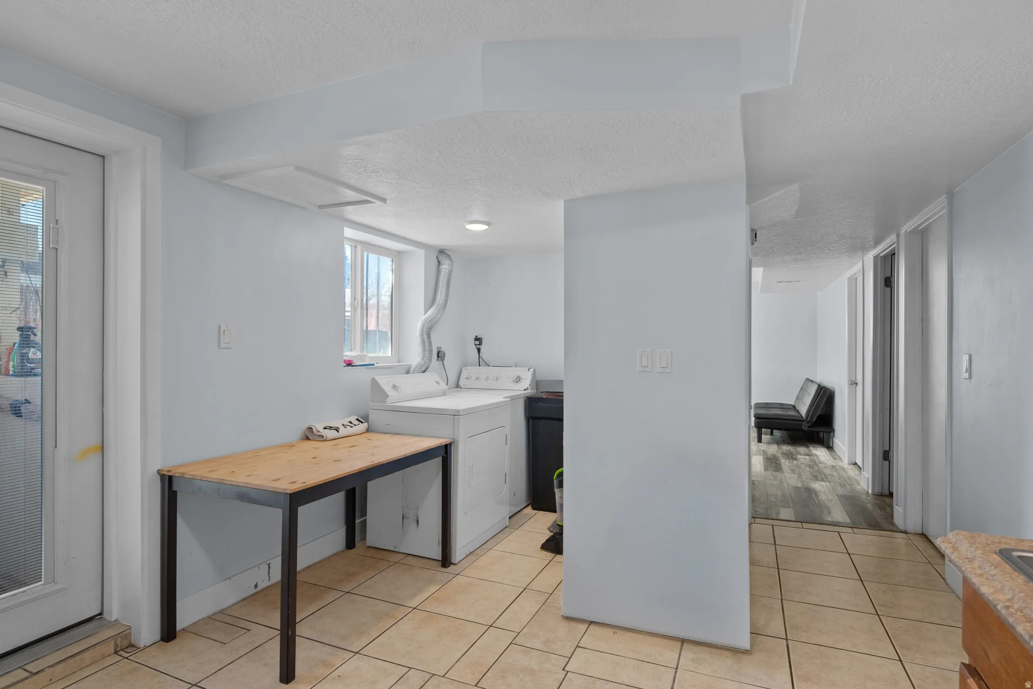 Laundry room featuring a textured ceiling, washer and dryer, and light tile patterned floors