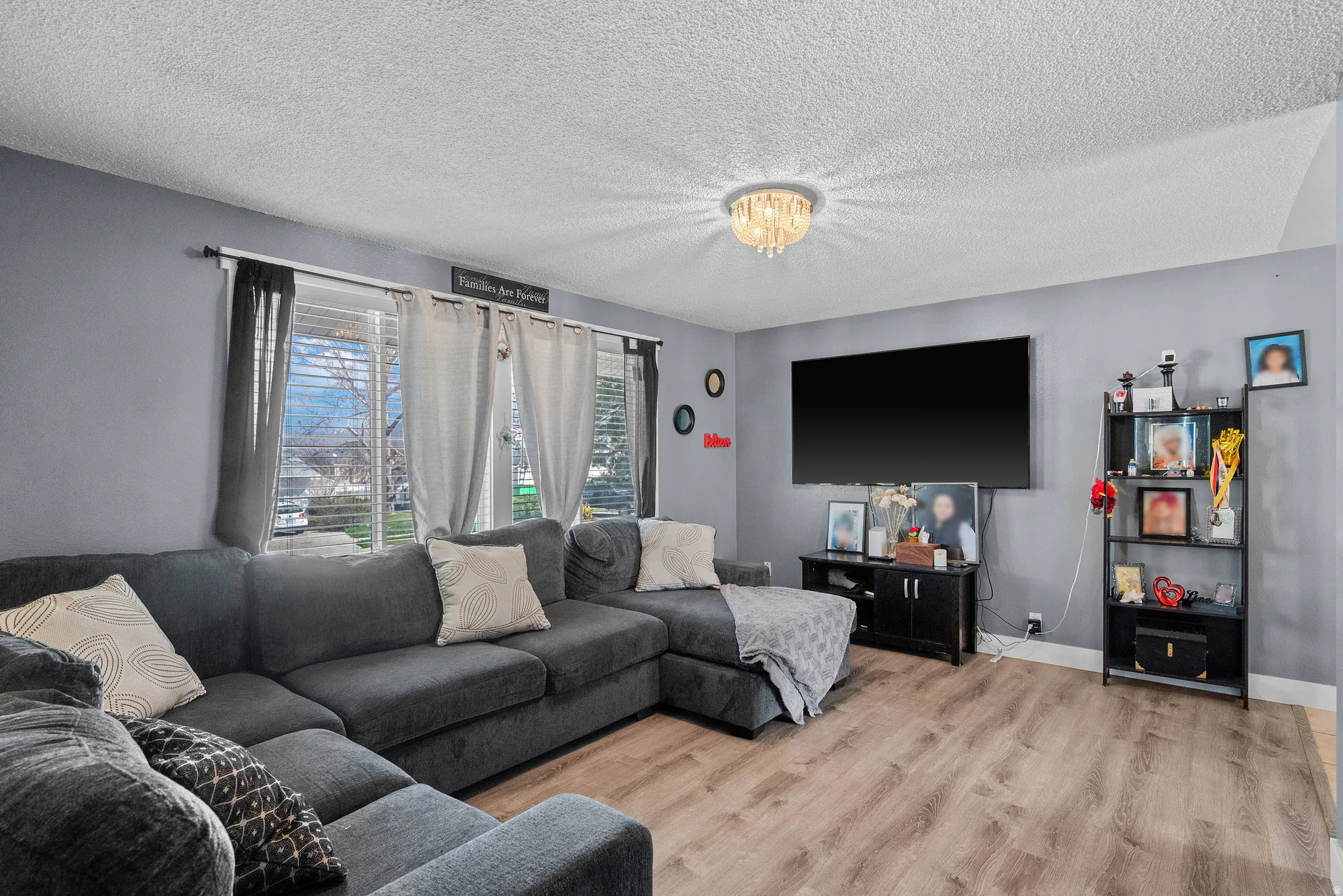 Living area with a textured ceiling, wood finished floors, and a chandelier