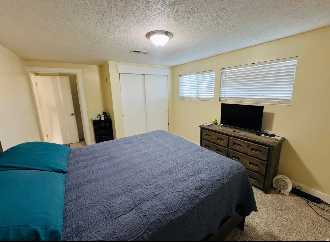 Bedroom featuring a textured ceiling, a closet, and light colored carpet