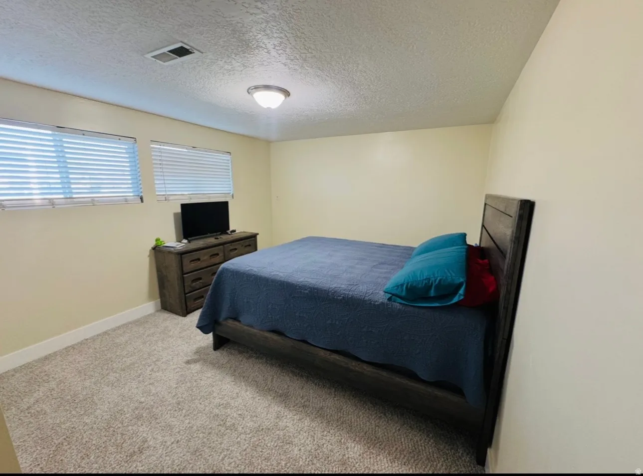 Bedroom with light colored carpet and a textured ceiling