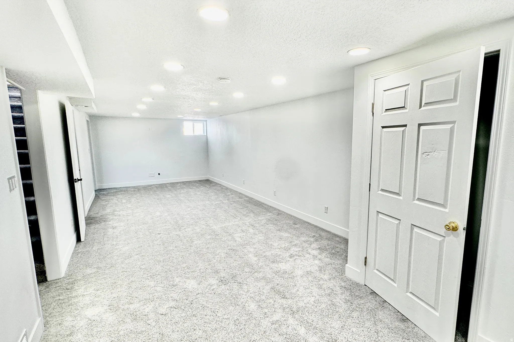 Basement featuring light colored carpet, a textured ceiling, and recessed lighting