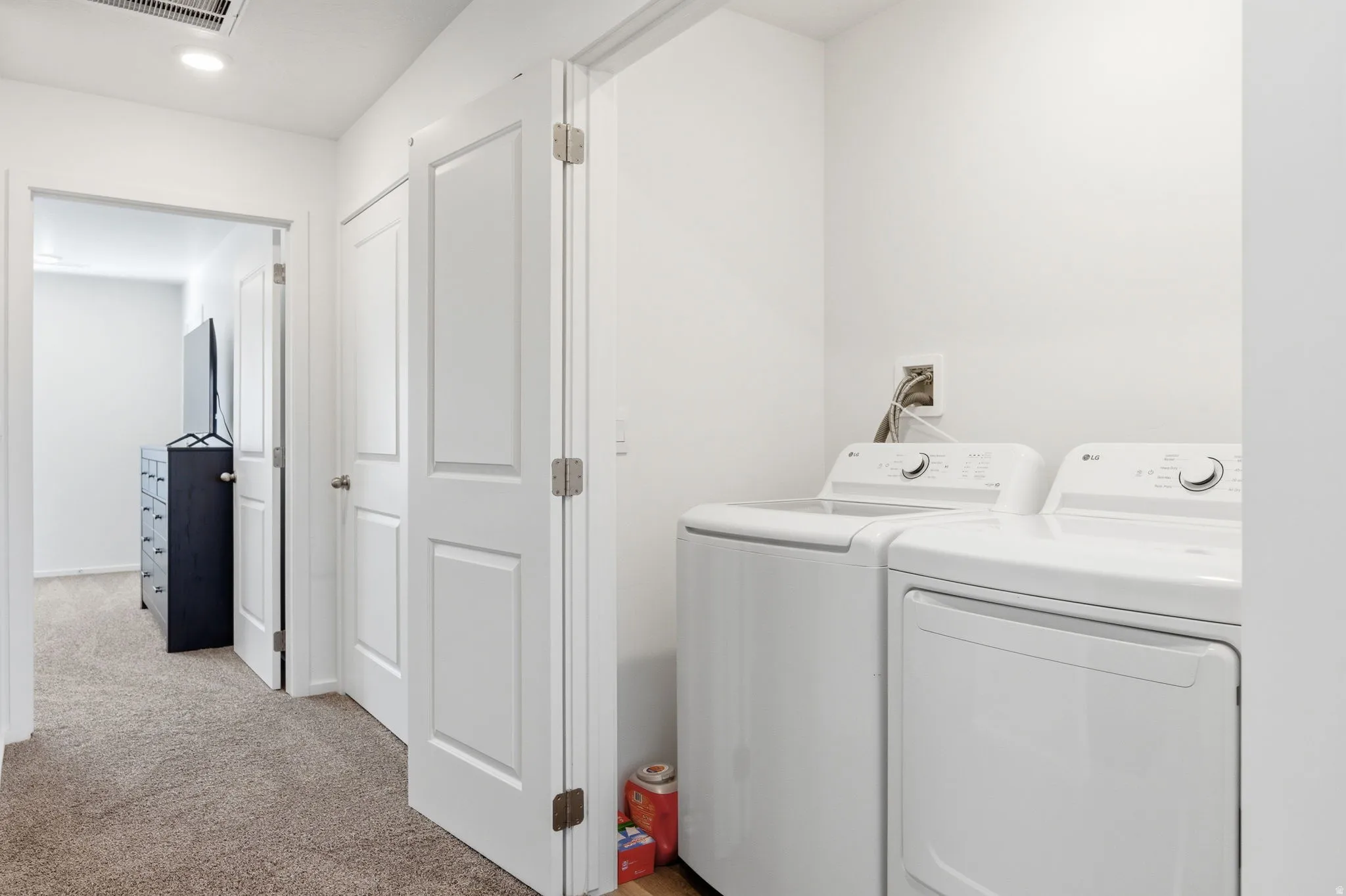 Laundry area featuring light carpet and washing machine and clothes dryer