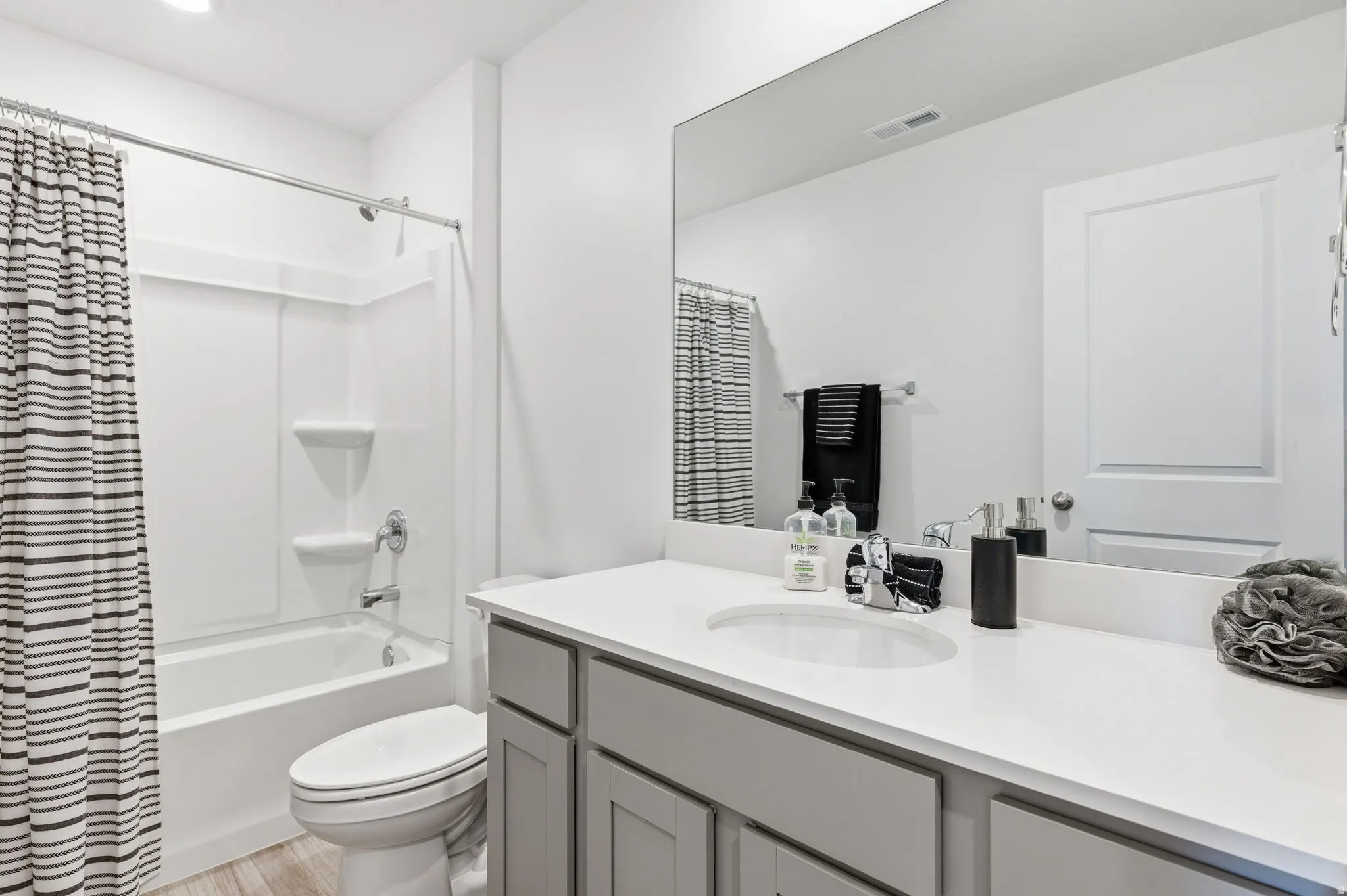 Full bathroom featuring vanity, light wood-type flooring, and shower / bath combination with curtain
