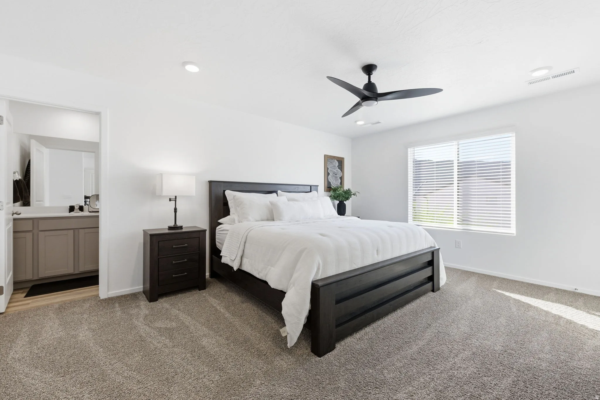 Primary Bedroom with light colored carpet, a ceiling fan, and connected bathroom