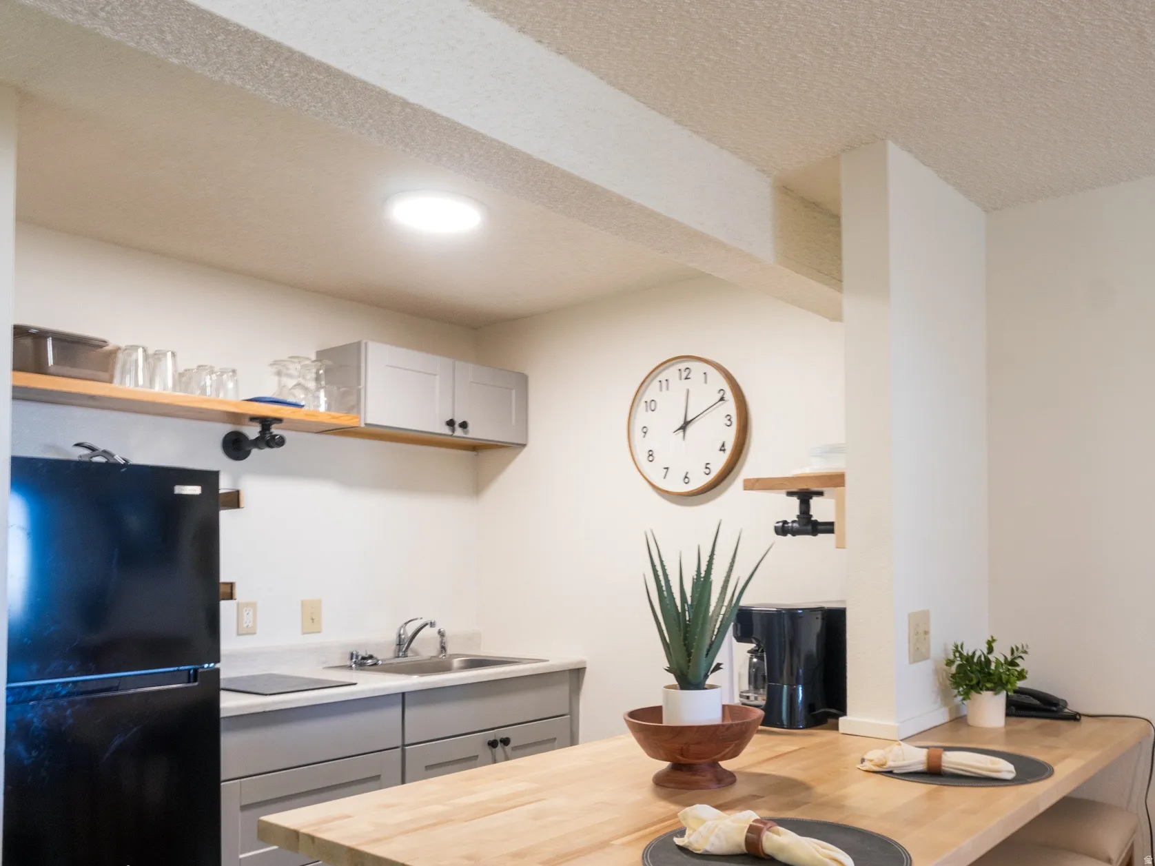Kitchen featuring gray cabinetry, a breakfast bar, wood counters, freestanding refrigerator, and a peninsula