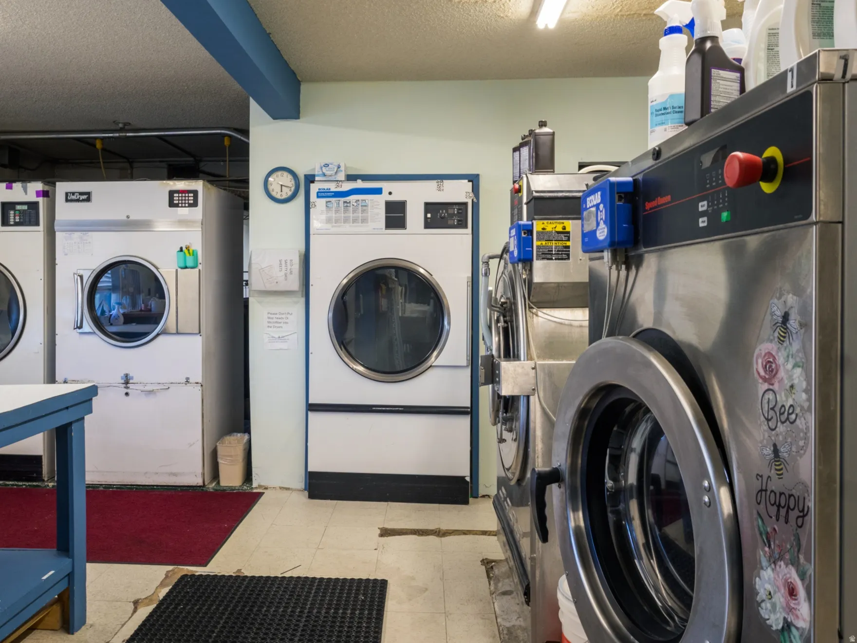 Shared laundry room with independent washer and dryer and a textured ceiling