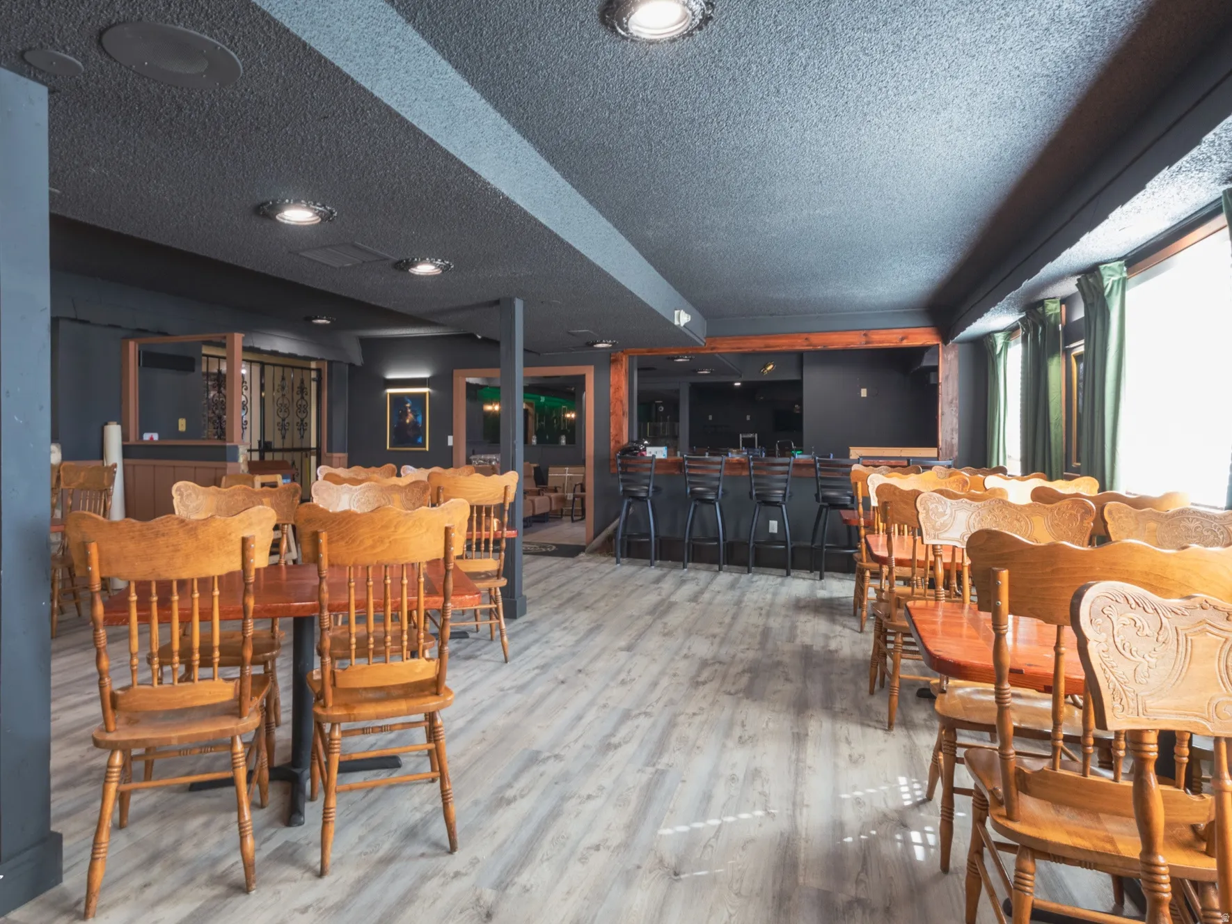 Dining area with bar area, light wood-style floors, and a textured ceiling