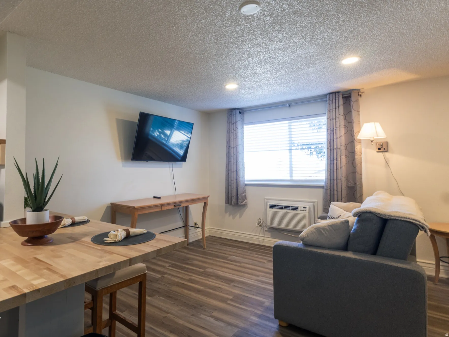 Living area featuring dark wood finished floors, a textured ceiling, and recessed lighting