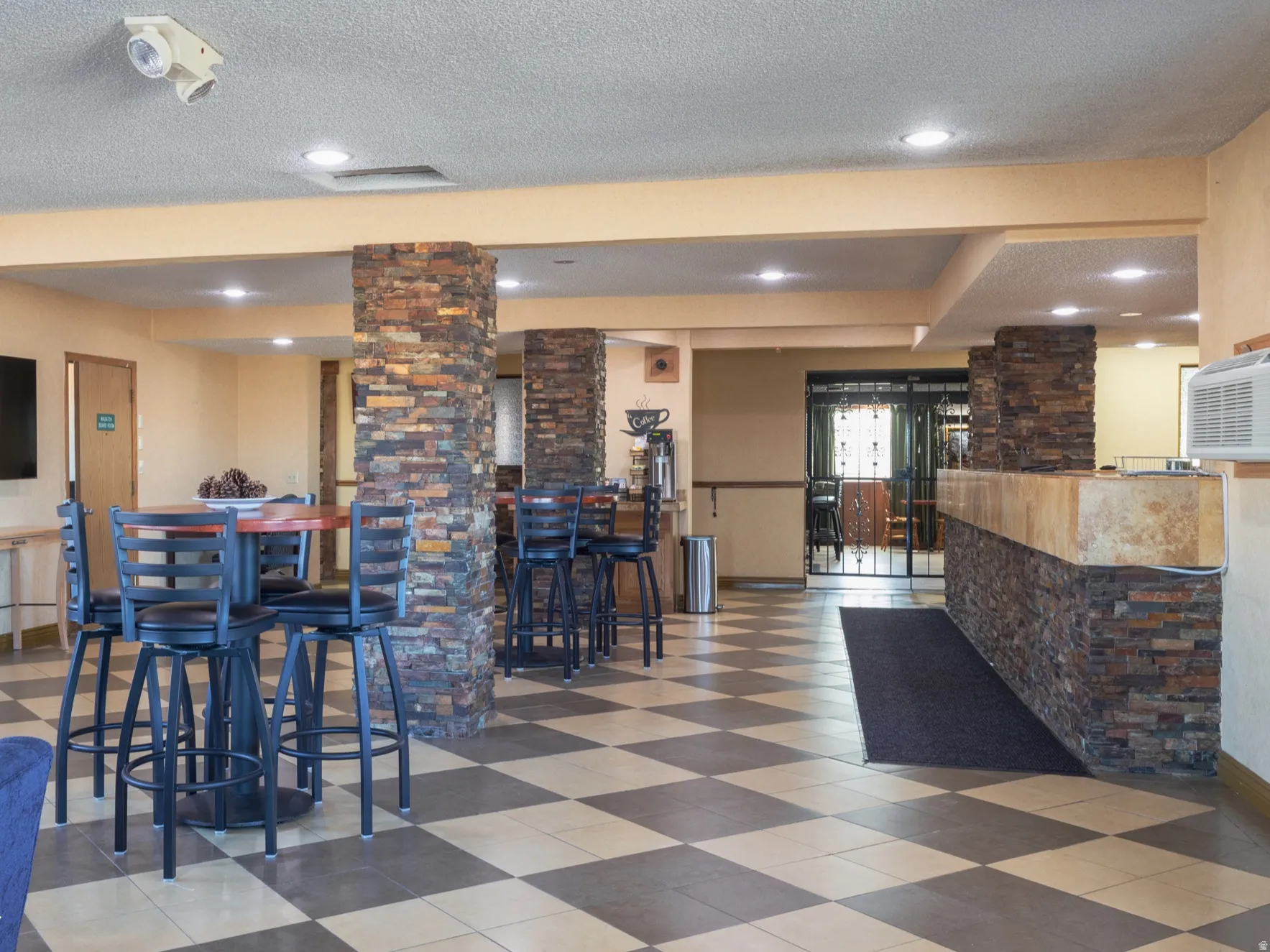 Dining area with a textured ceiling, decorative columns, recessed lighting, and tile patterned floors