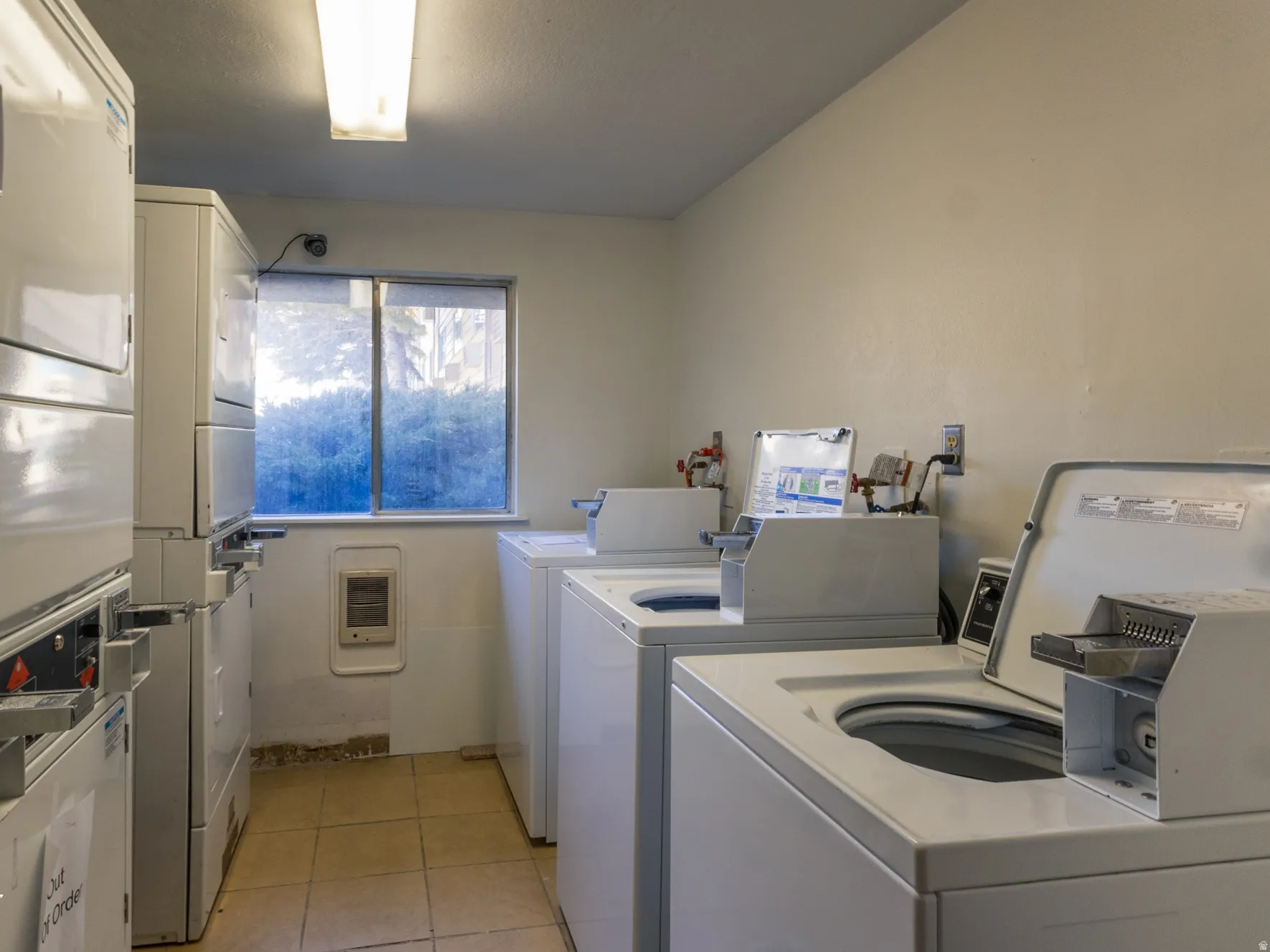 Community laundry room featuring heating unit and washing machine and clothes dryer
