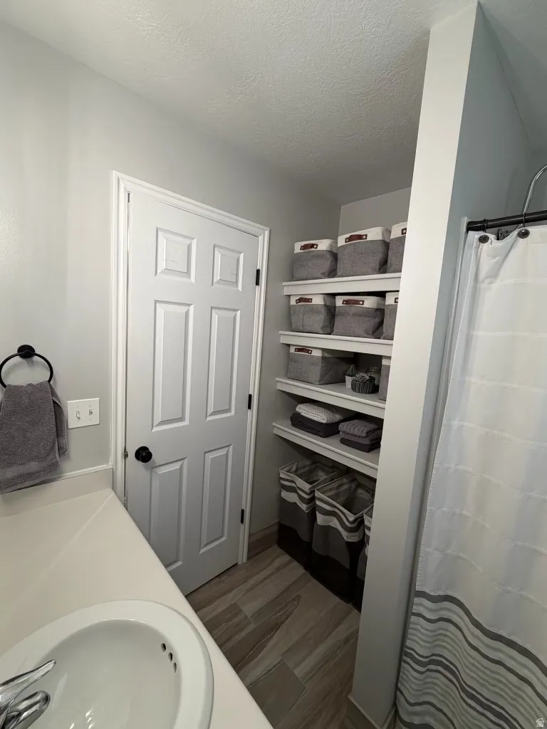 Bathroom with vanity, a shower with curtain, dark wood finished floors, and a textured ceiling
