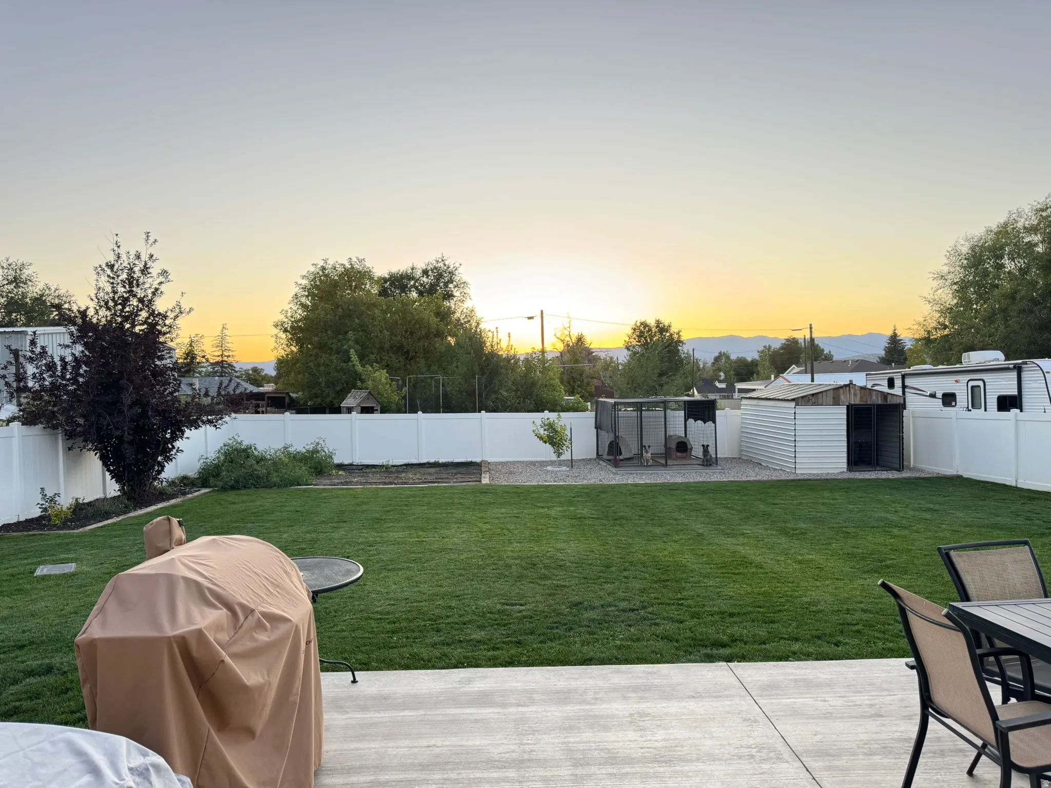 Fenced backyard featuring a patio, outdoor dining space, and an outbuilding