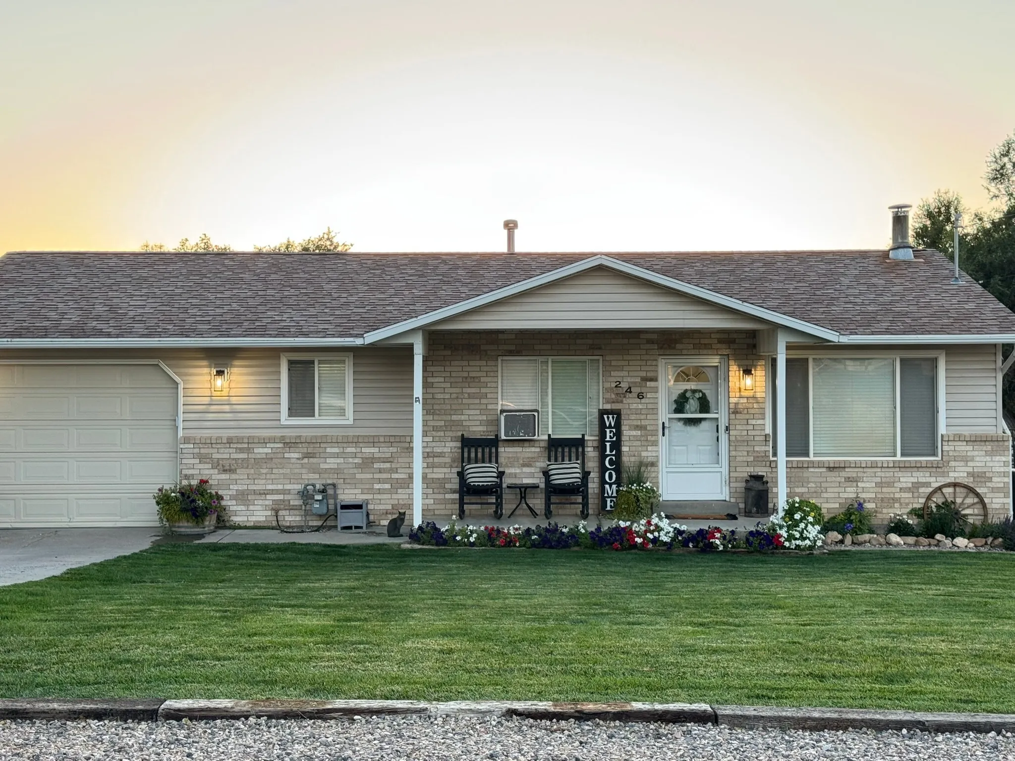 Single story home featuring a front lawn, a porch, brick siding, and an attached garage