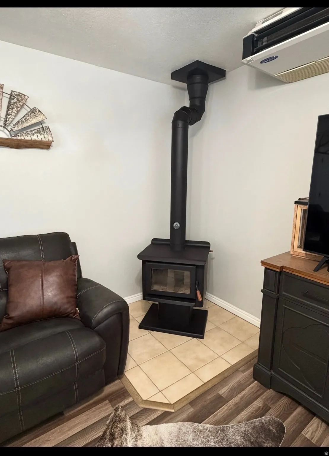 Detailed view of wood finished floors, a wood stove, and a heating unit