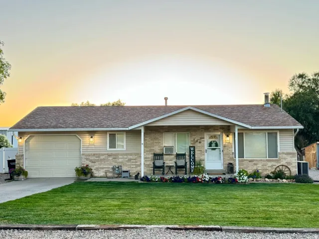 Single story home featuring a front yard, a porch, an attached garage, and brick siding